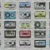 Gri beton zemin üzerine düzenli bir şekilde dizilmiş, üzerinde farklı grafitiler ve neon renkler bulunan retro müzik kasetleri içeren duvar kağıdı