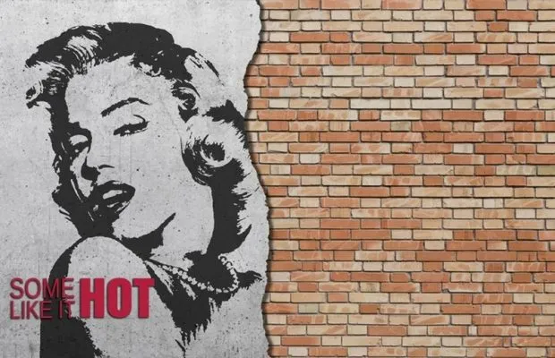 Tuğla duvar üzerine sokak sanatı stilinde işlenmiş Marilyn Monroe portresi ve Some Like It Hot yazılı duvar kağıdı.