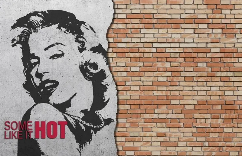 Tuğla duvar üzerine sokak sanatı stilinde işlenmiş Marilyn Monroe portresi ve Some Like It Hot yazılı duvar kağıdı.