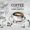 Beyaz tuğla duvar üzerinde "Coffee Than Compliments" yazılı, kahve fincanı ve çekirdekleri illüstrasyonlu duvar kağıdı.