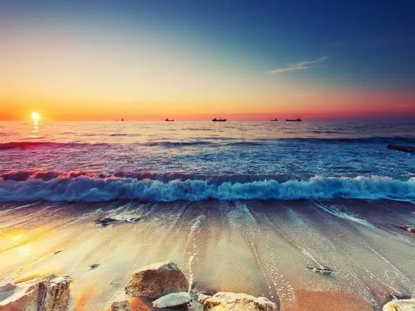 Gün batımı saati sahile vuran dalgalar ve kıyıdaki kayalıklar temalı 3D derinlik etkili duvar posteri.