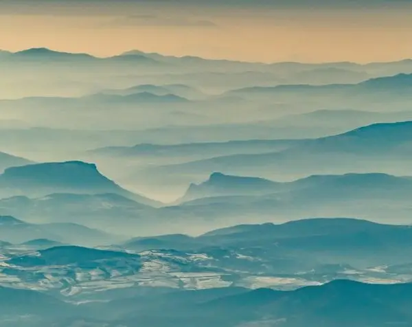 Sisler içinde mavi sıra dağlar ve puslu gökyüzü temalı katmanlı manzara duvar posteri.