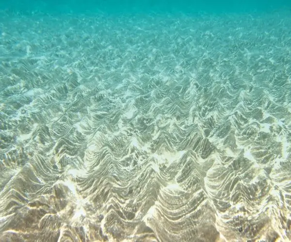 Denizin dibindeki kum dalgaları ve su yüzeyinden süzülen güneş ışığı yansımalı dikişsiz duvar posteri.