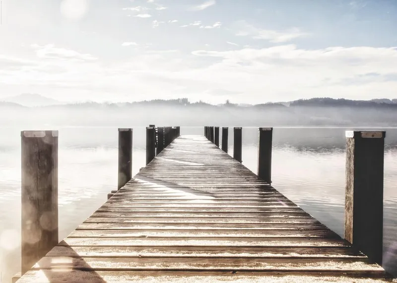 Sisler içinde sonsuzluk hissi veren ahşap iskele ve dingin göl manzaralı dijital baskı duvar posteri.